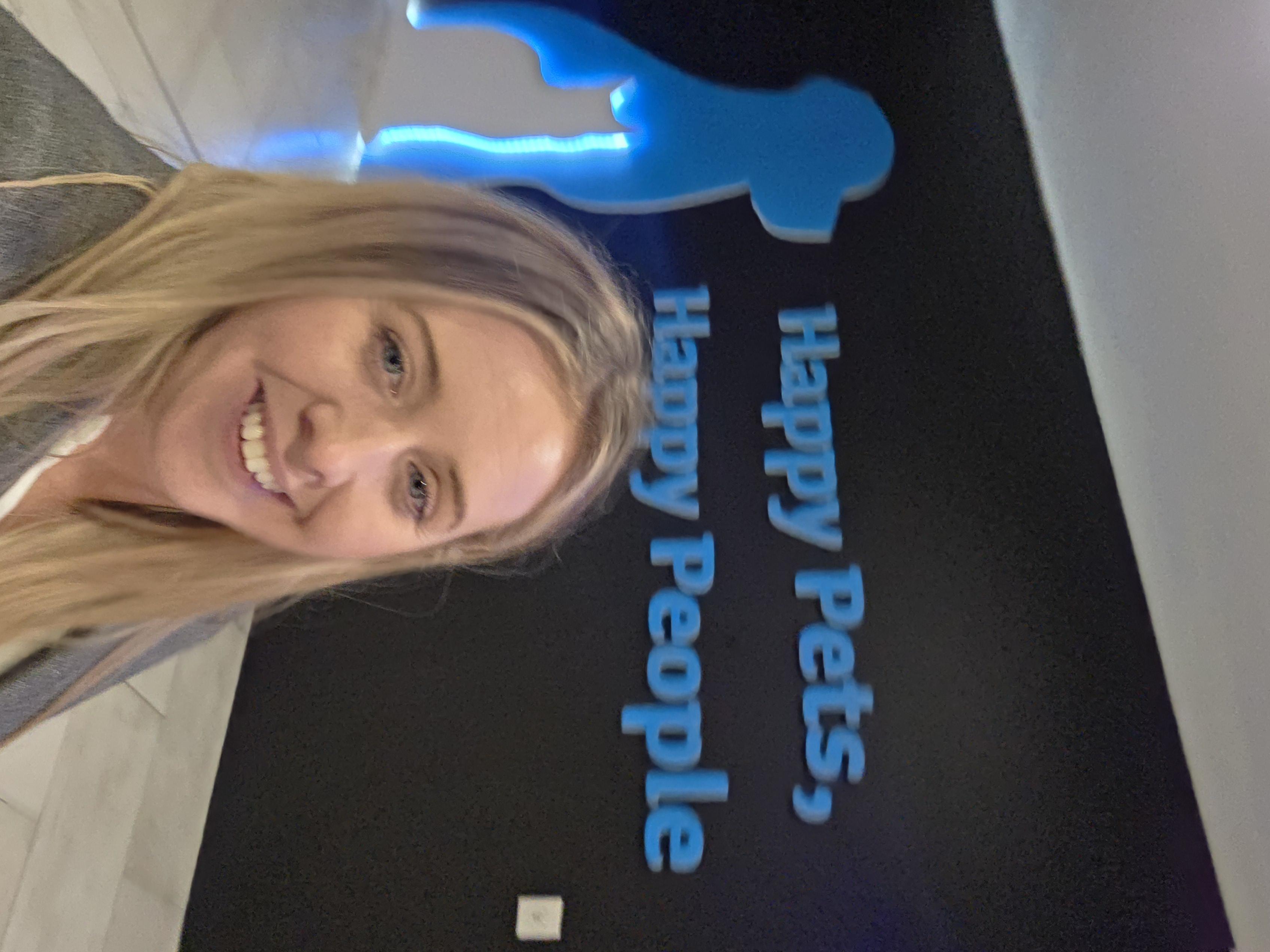Louise Lally in front of a Petstop wall reading &lsquo;Happy Pets, Happy People&rsquo;